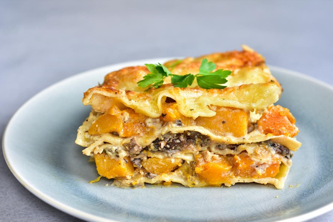 kawałek lasagne z dynią i grzybami na talerzu