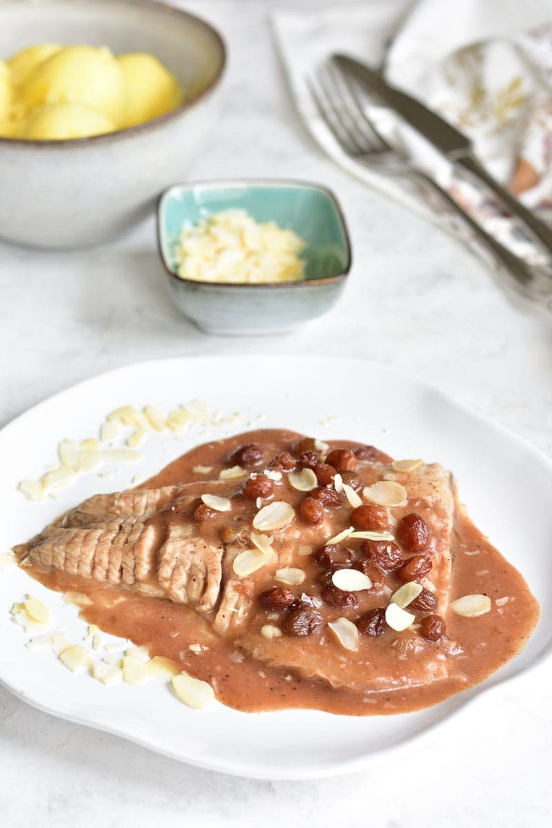 Fish with gingerbread sauce (Carp in old Polish gray sauce) on a white plate