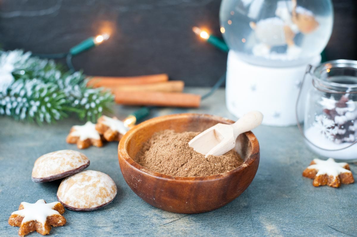 Gingerbread spice mix in a brown bowl. Christmas decoration in the background.