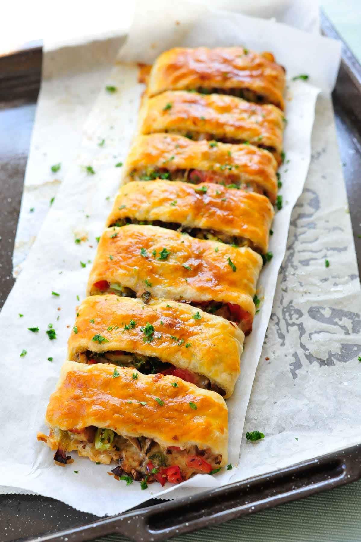 Puff pastry strudel with vegetables and cheese on a baking sheet.