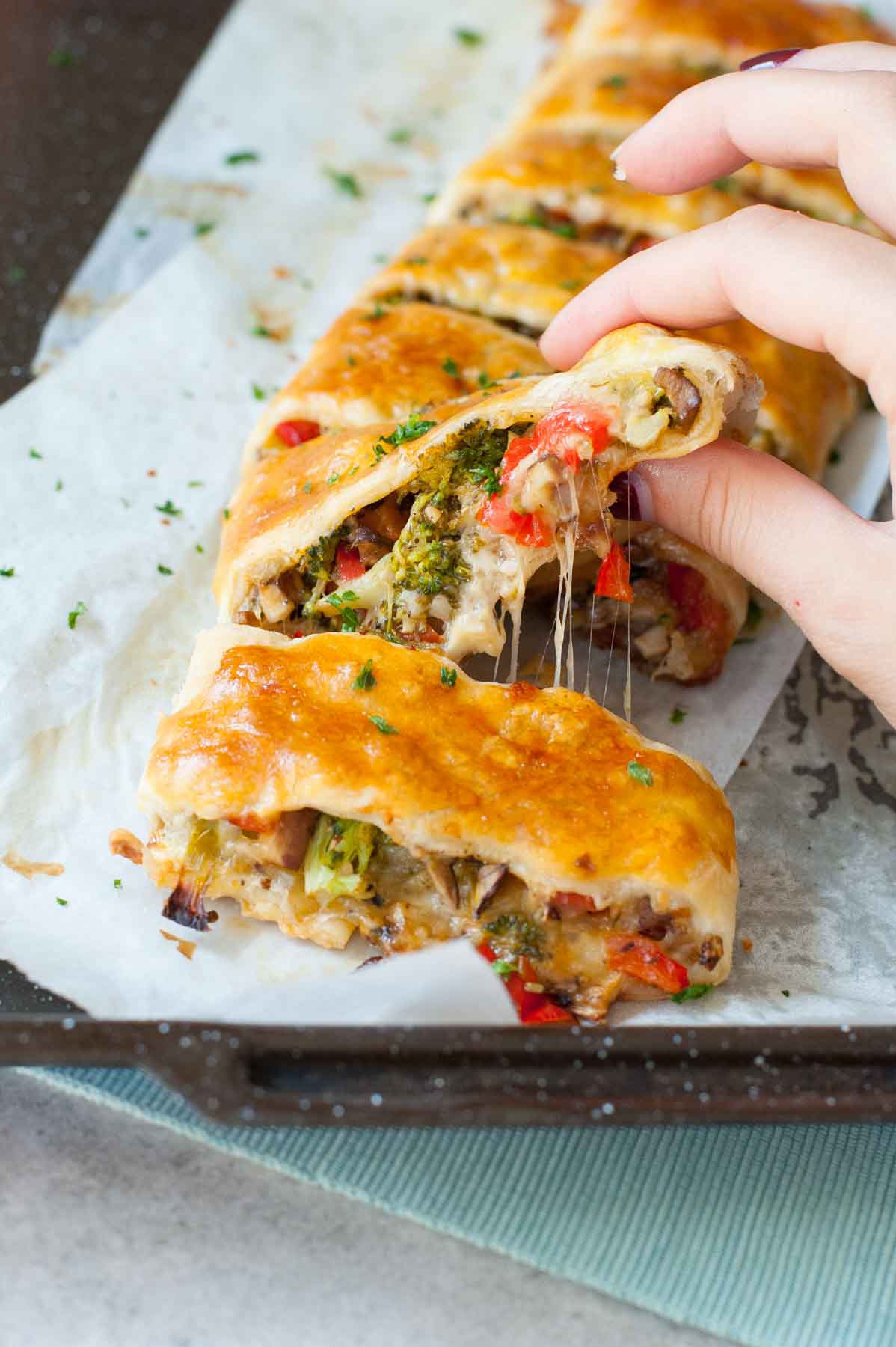 Puff pastry strudel with vegetables and cheese on a piece of baking paper.
