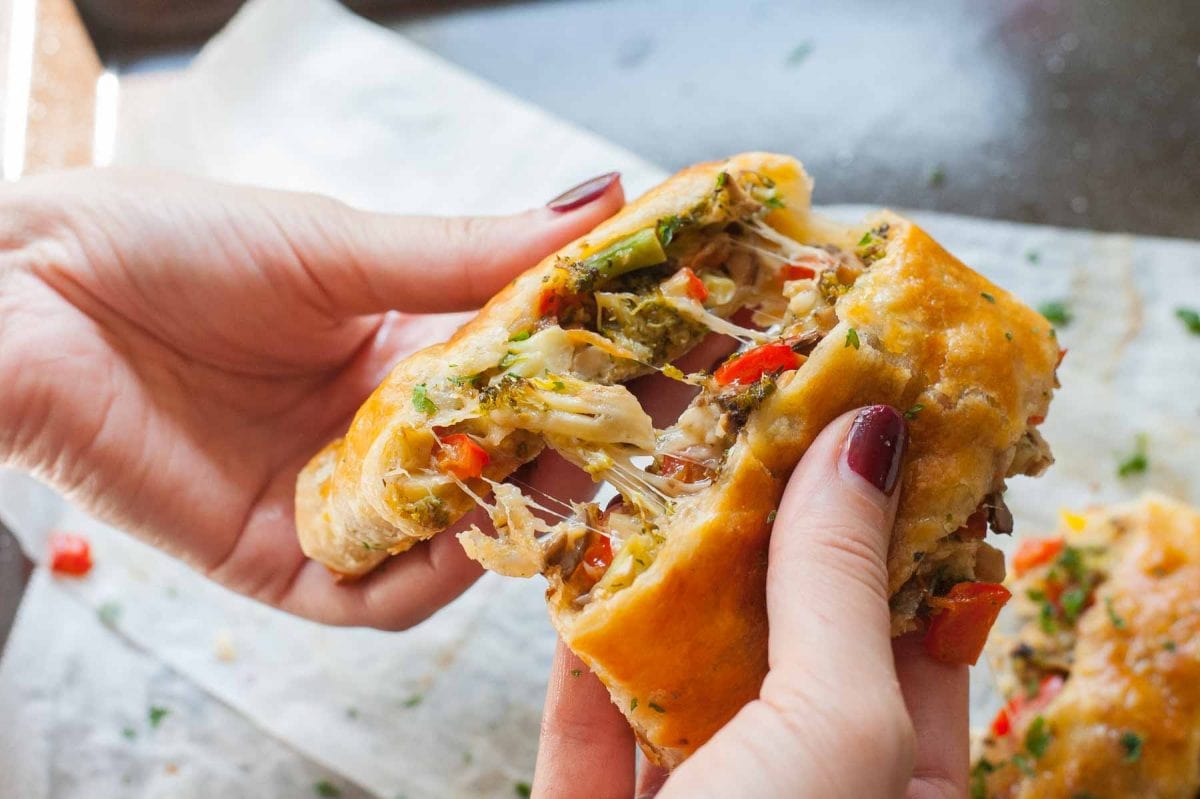 Puff pastry strudel with vegetables and cheese in hands.