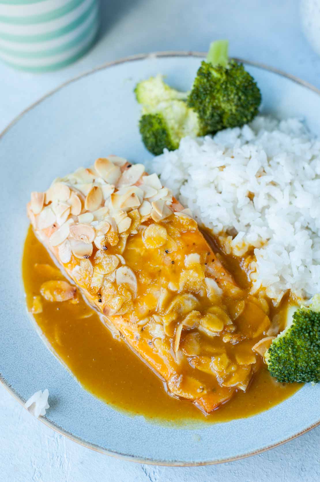 A close up picture of salmon with almonds and orange ginger sauce, served with coconut rice.