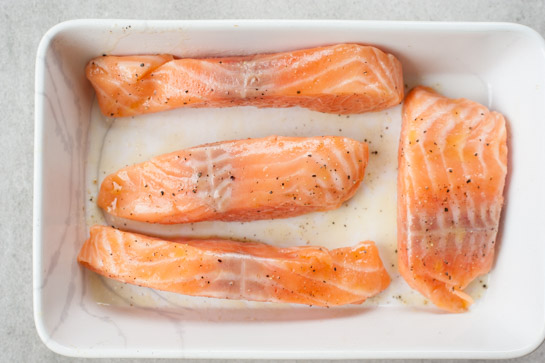 Raw salmon fillets in a baking dish.