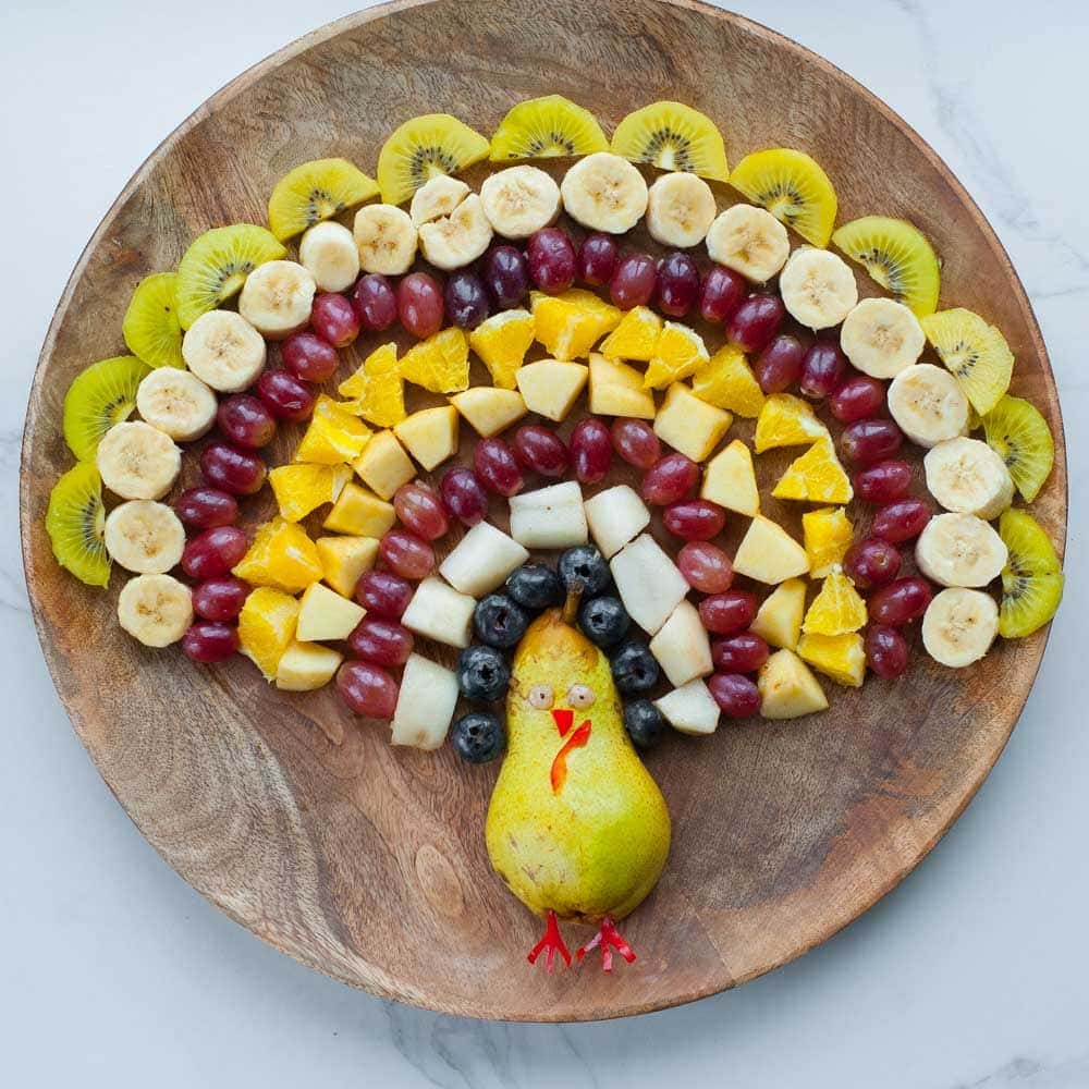 turkey fruit plattes - chopped fruits arranged in a shape of turkey on a wooden board
