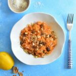 white plate with carrot apple salad on a blue background