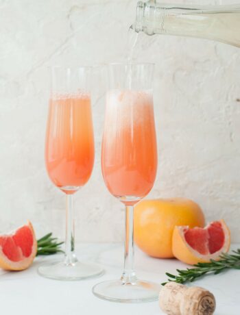 two champagne glasses filled with grapefruit mimosa
