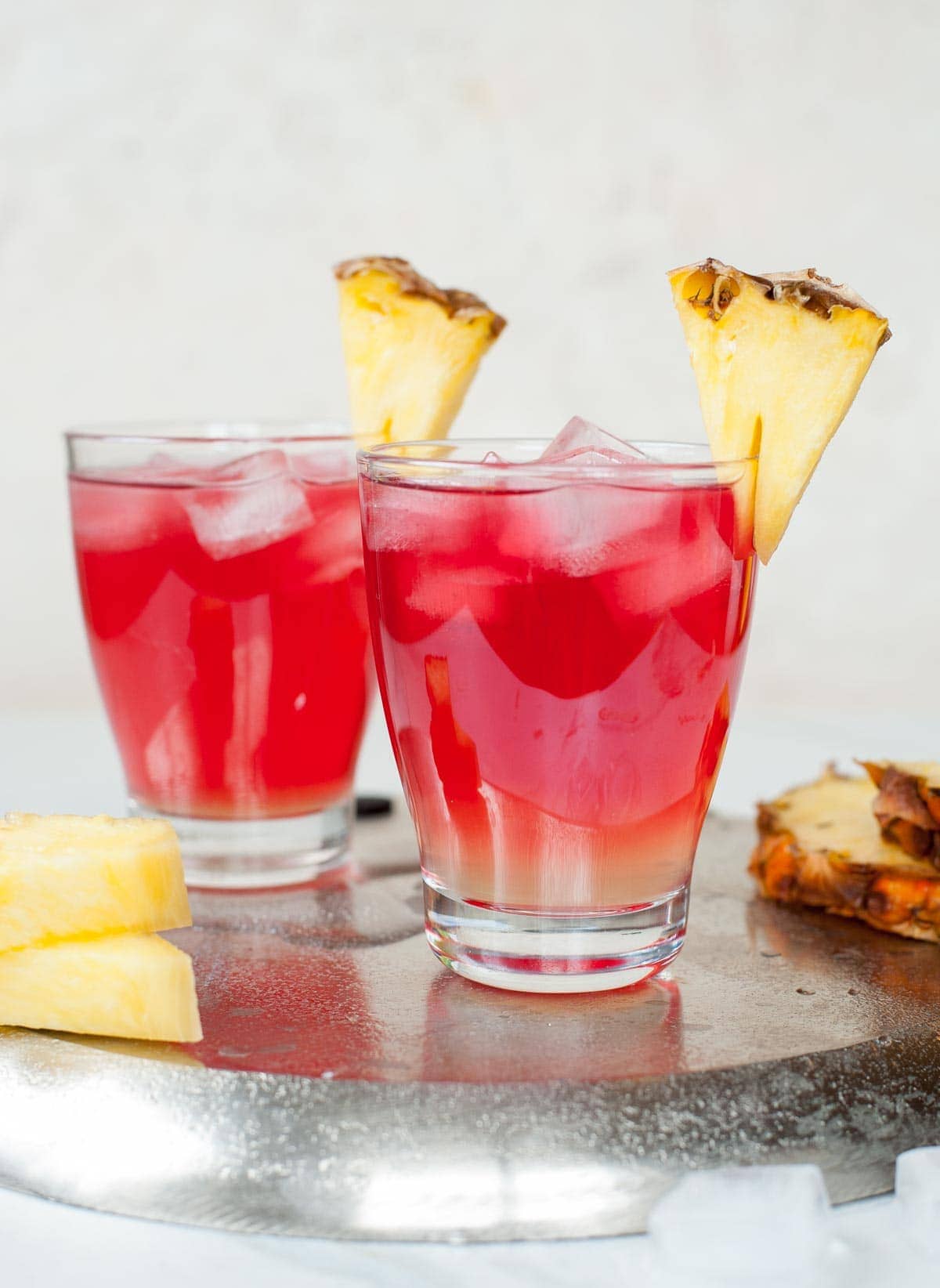 Malibu bay breeze drink in two glasses garnished with pineapple wedges.