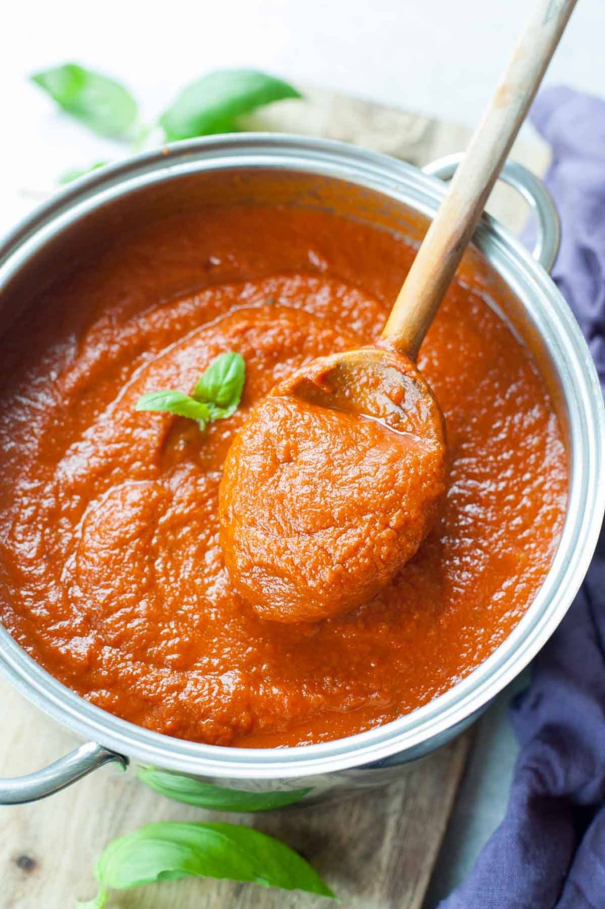 Meatless tomato sauce in a pot is being scooped with a wooden spoon.