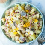 herring salad with potatoes and eggs in a green bowl