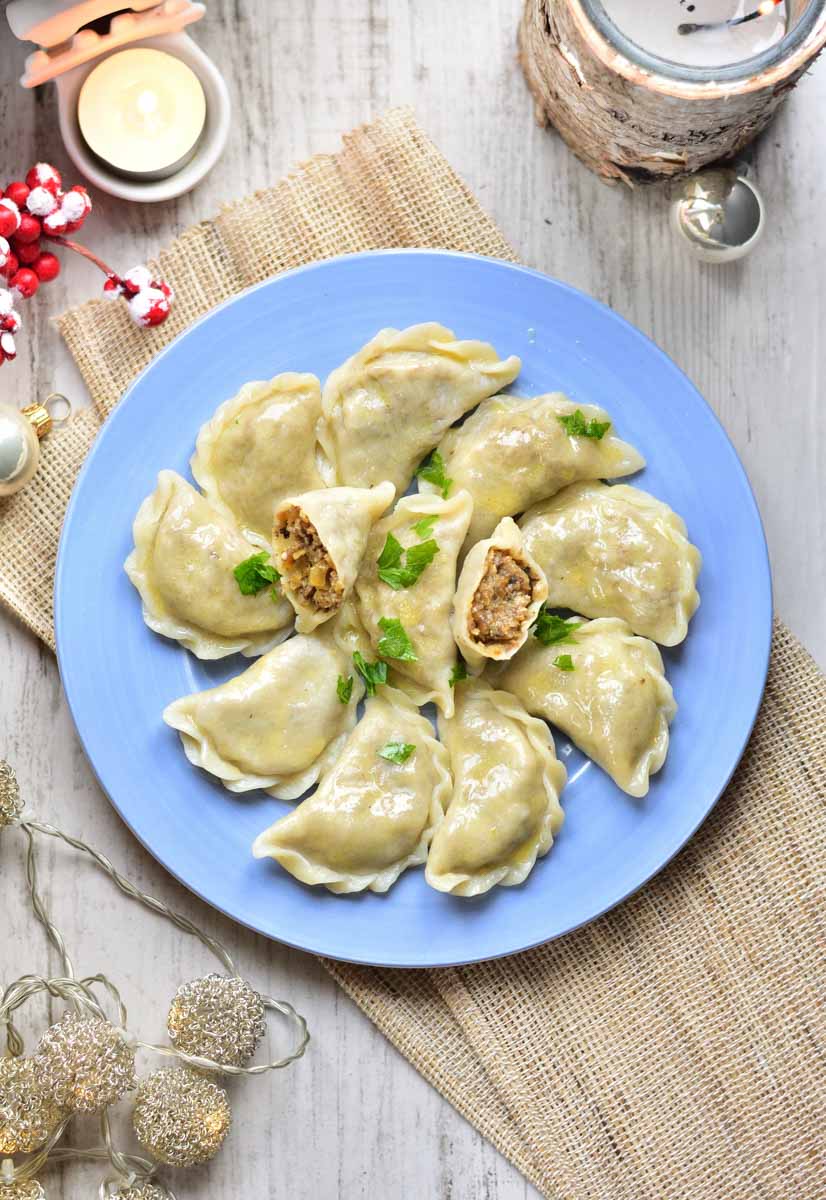 Sauerkraut and mushroom pierogi on a blue plate, sprinkled with parsley.