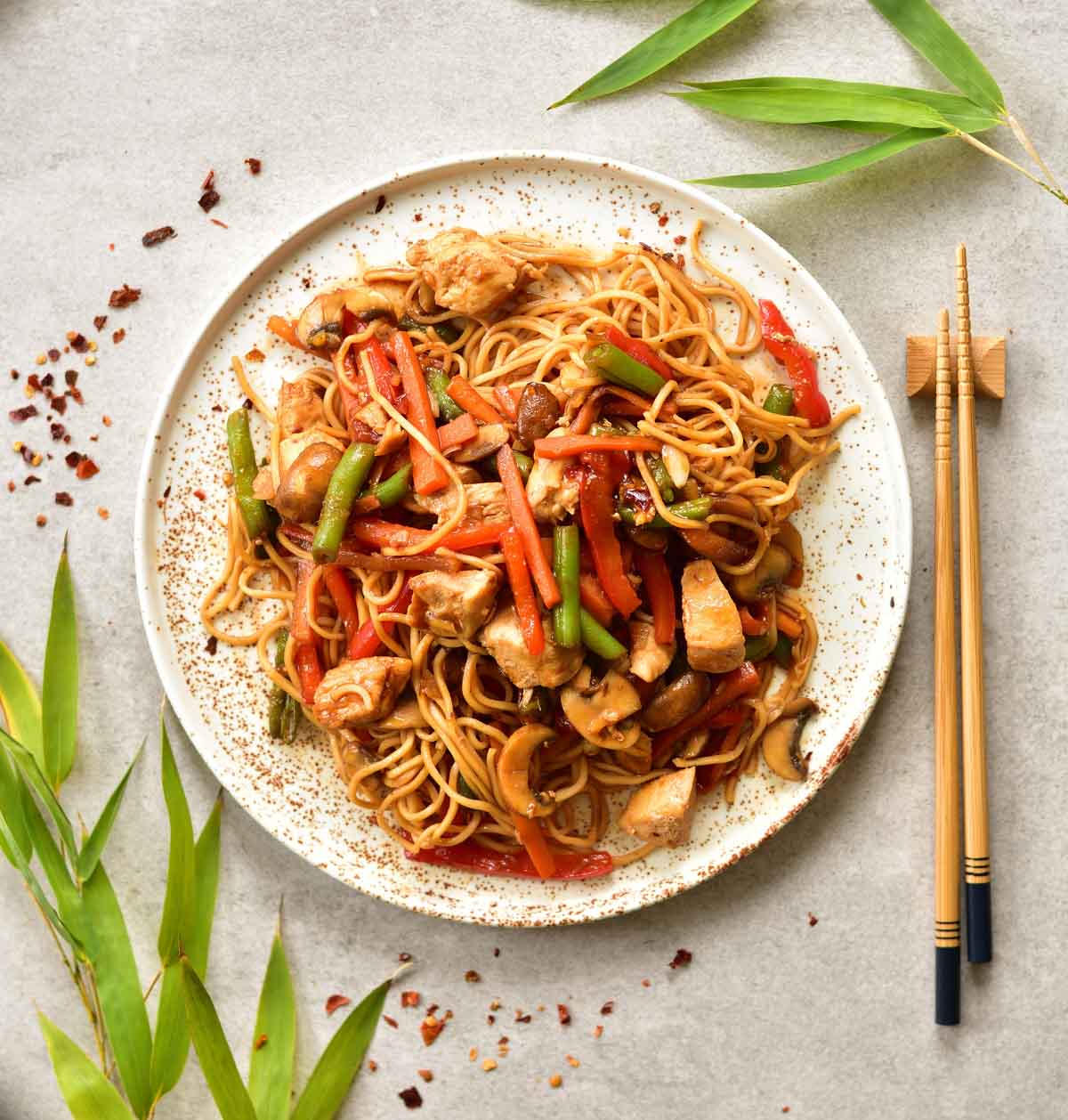 Sweet and sour chicken with noodles and vegetables on a white plate