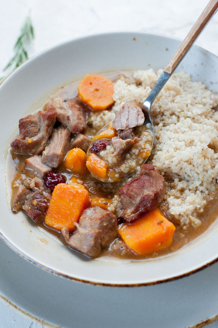 Turkey stew with sweet potatoes and cranberries with pearl barley in a grey plate.