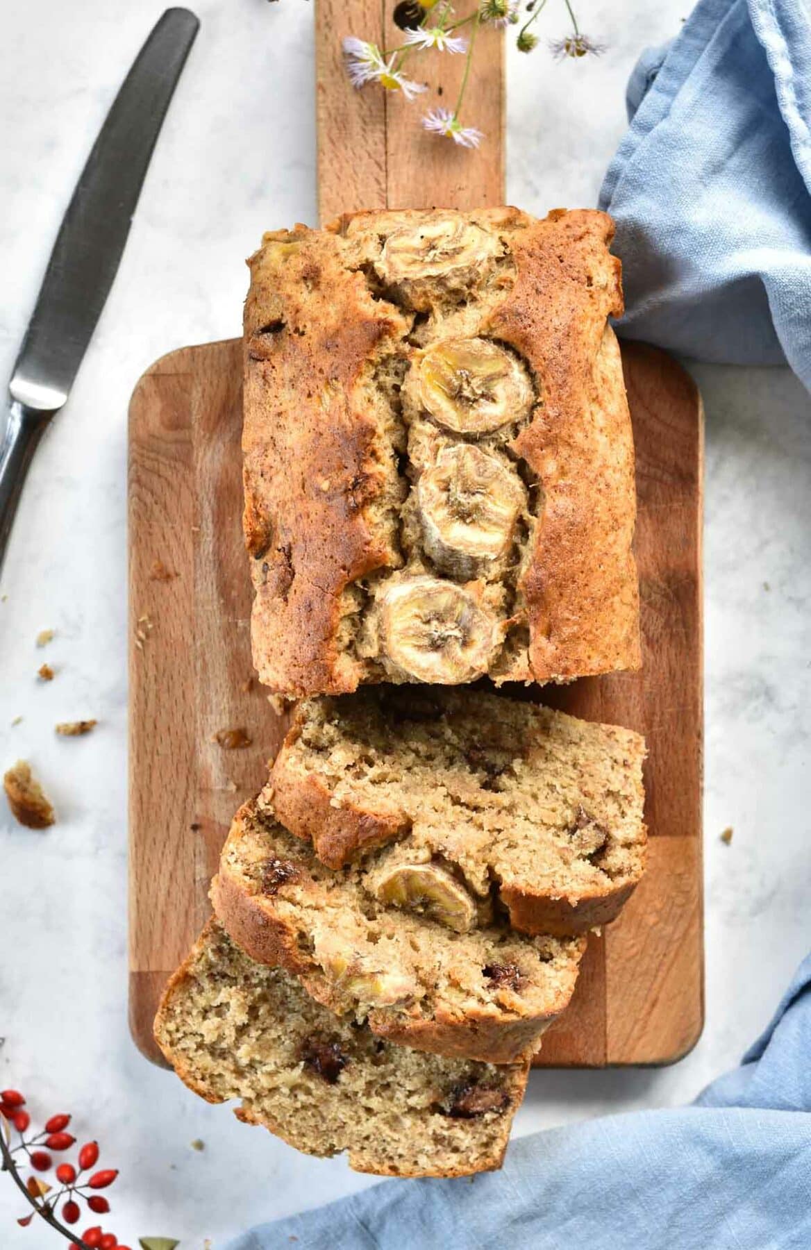Banana bread with chocolate and walnuts on a chopping board.