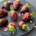 chocolate covered strawberries on a black plate