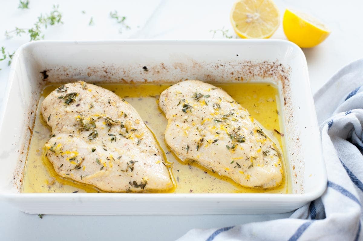 lemon thyme chicken breast in a white baking dish