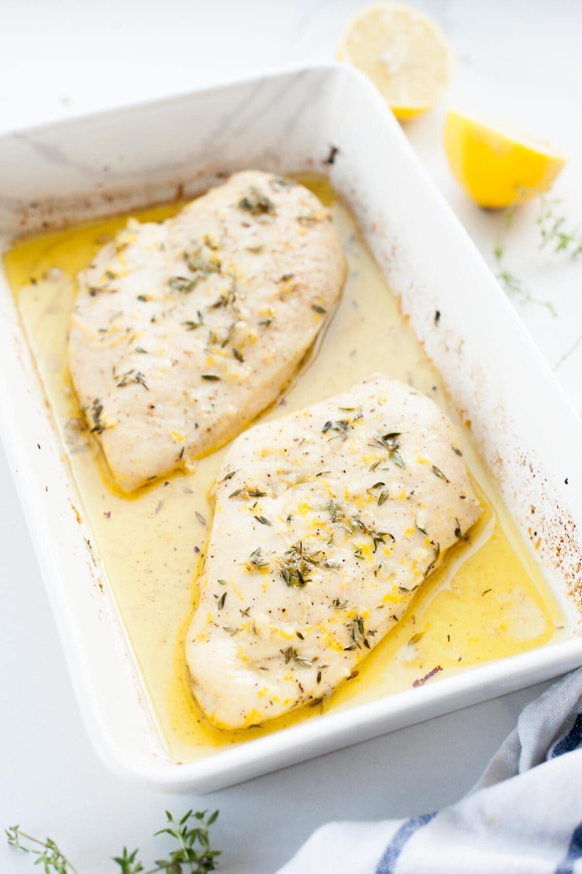 lemon thyme chicken breast in a white baking dish