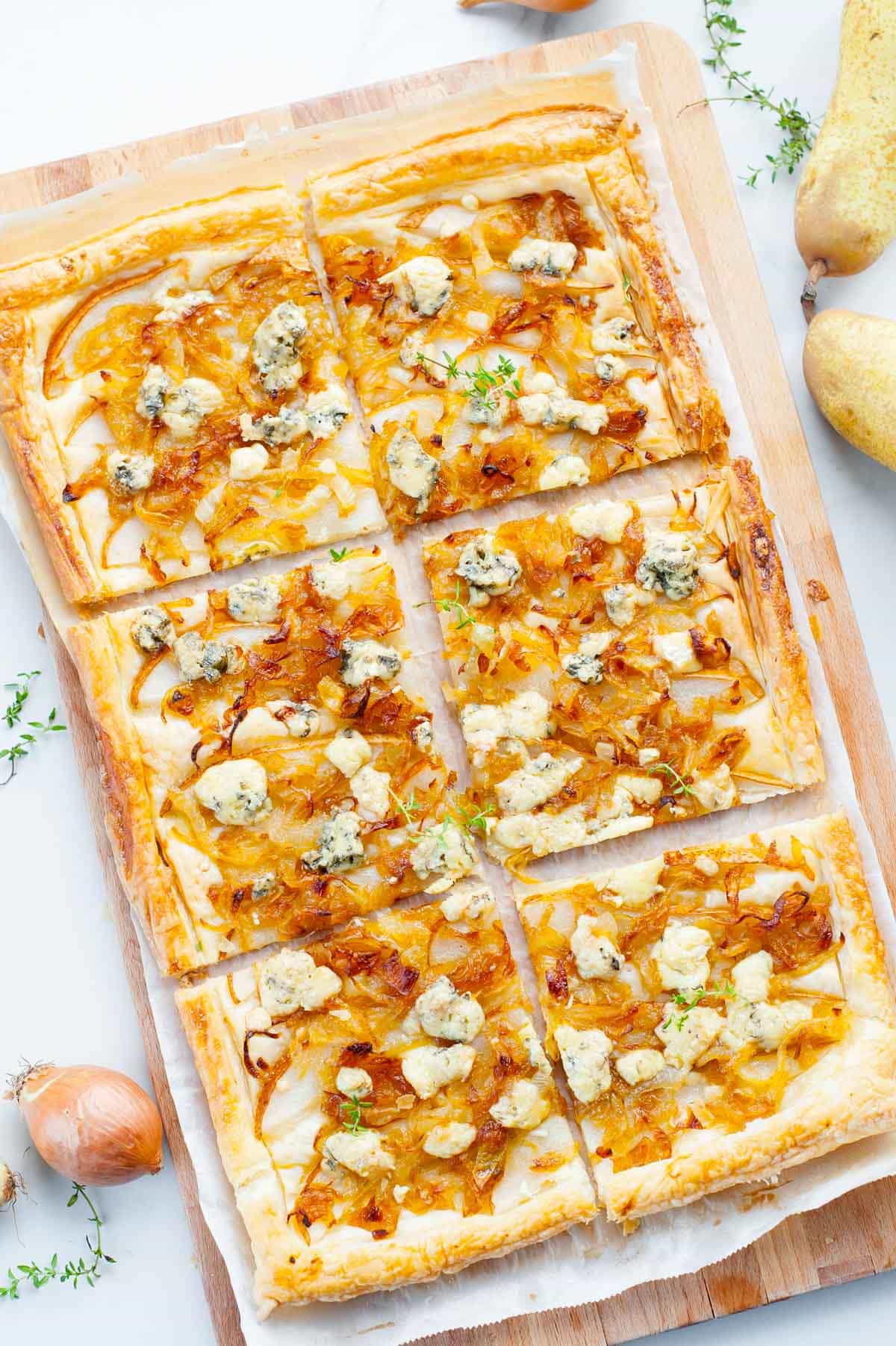 Puff pastry onion tart with pear and blue cheese on a wooden board.