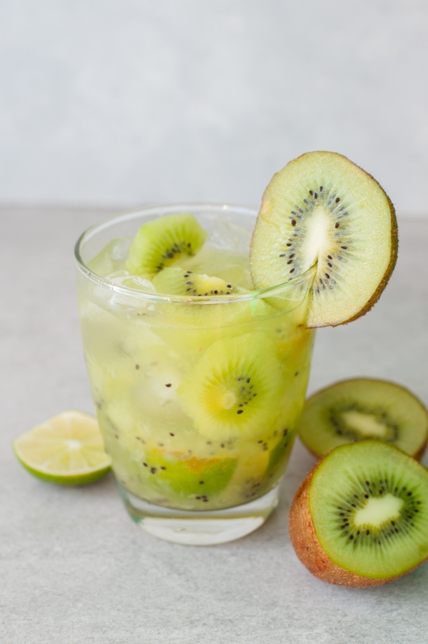 Kiwi caipirinha in a glass. Kiwi fruit on the side.