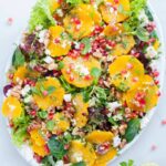 orange pomegranate salad with mint lime dressing on a white plate