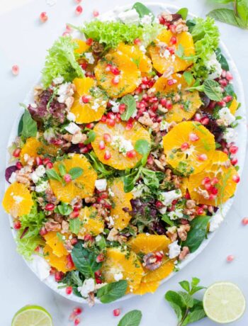 orange pomegranate salad with mint lime dressing on a white plate