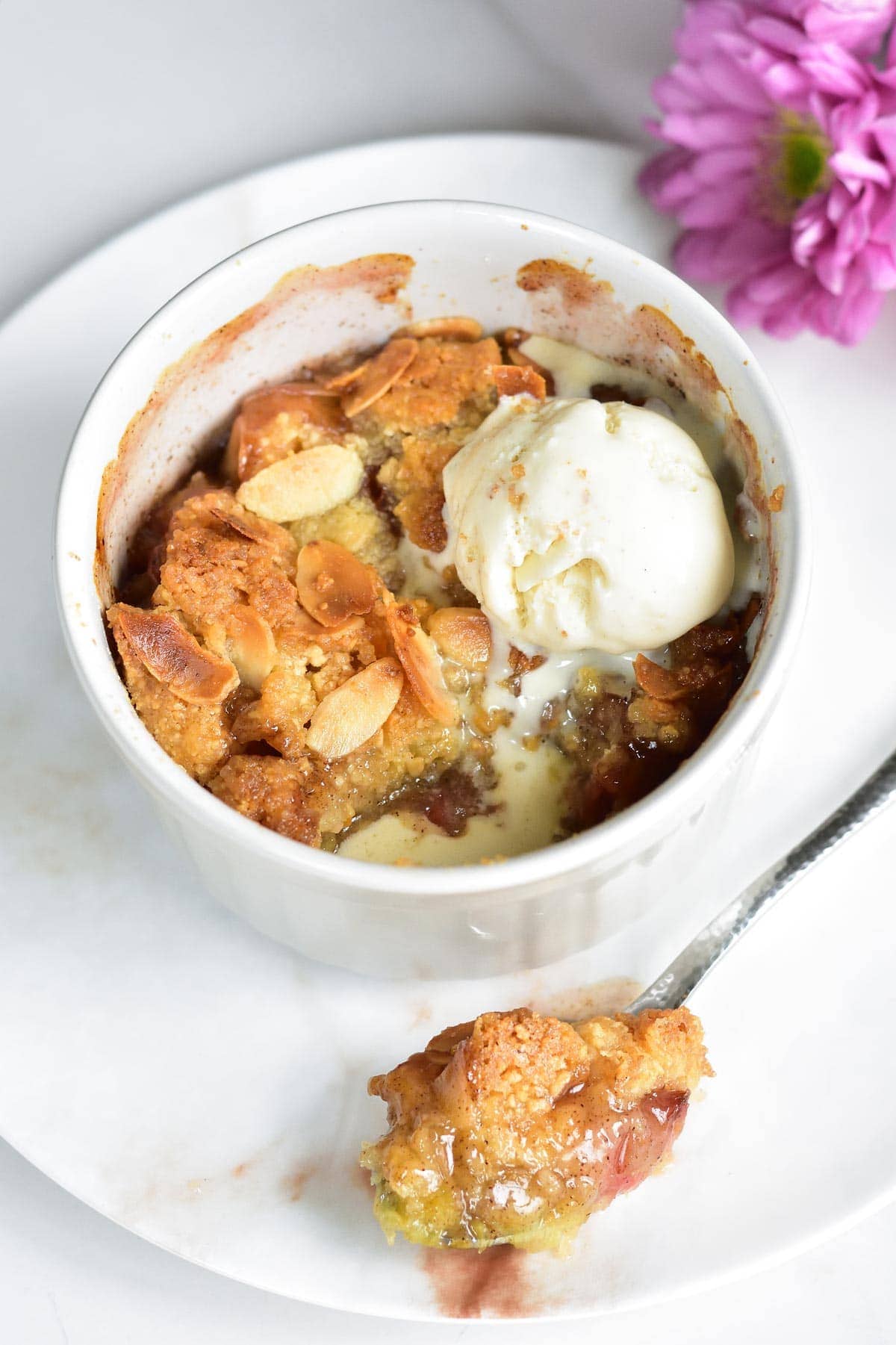 Rhubarb and almond crumble is a small ramekin with vanilla ice cream on top