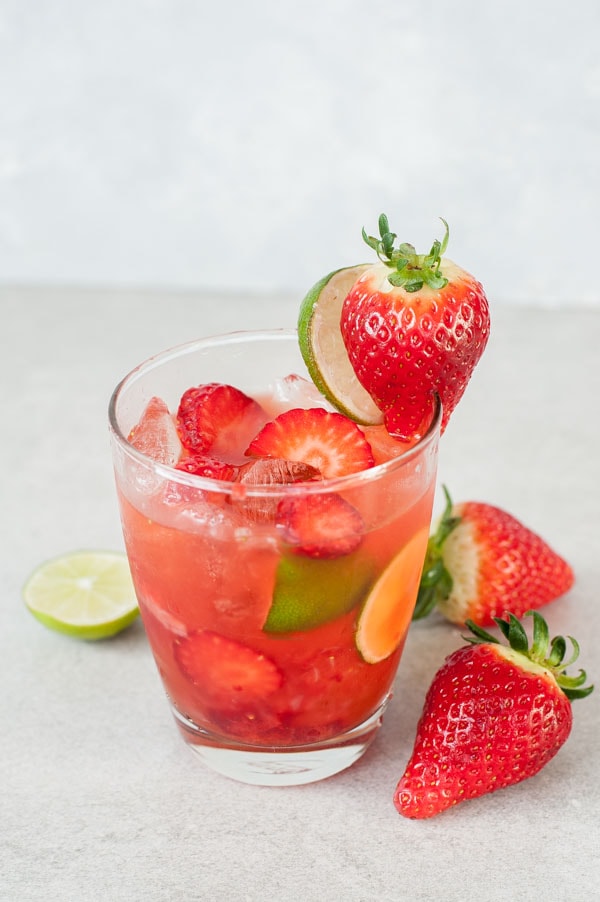 Strawberry caipirinha in a glass. Strawberries on the side of the glass.