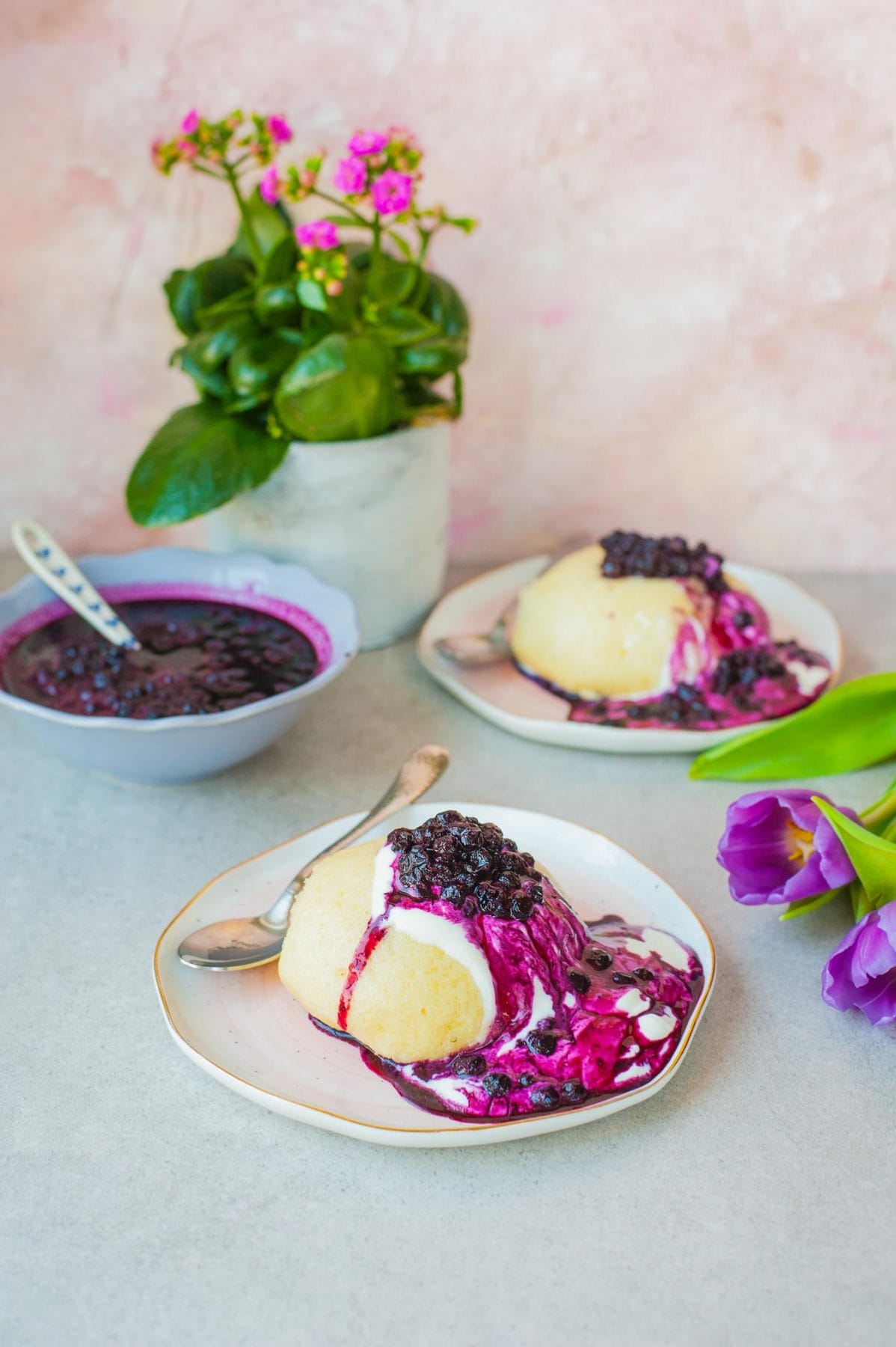 Two plates with steamed buns with blueberry sauce
