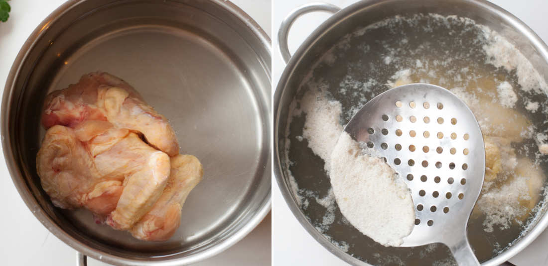 Chicken wings are being cooked in a pot. Foam is being scooped with a slotted spoon.