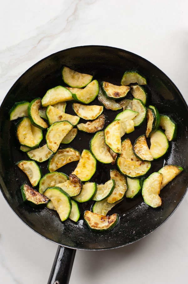 Cooked zucchini in a black frying pan.