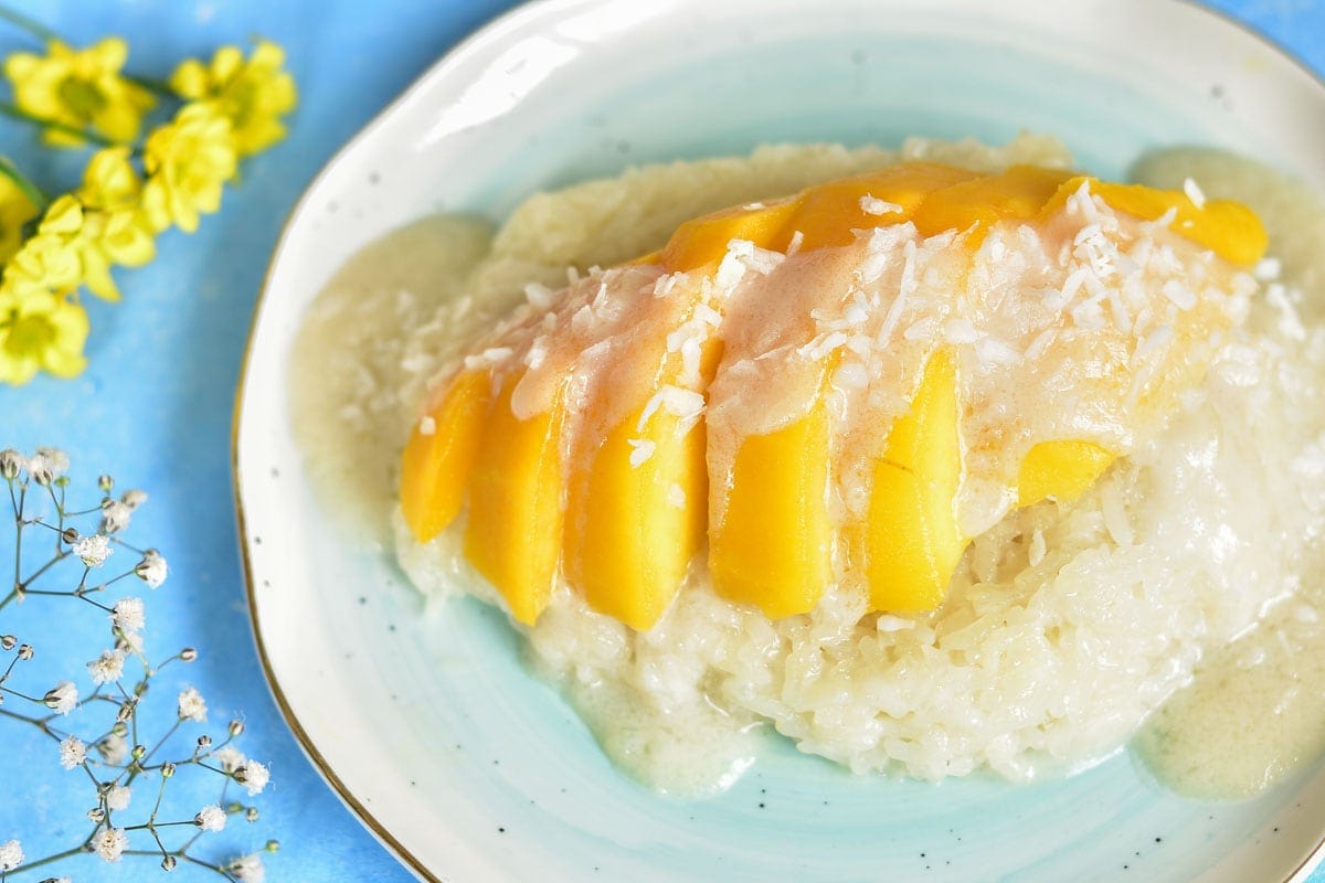 sticky rice with mango and coconut sauce on a light blue plate