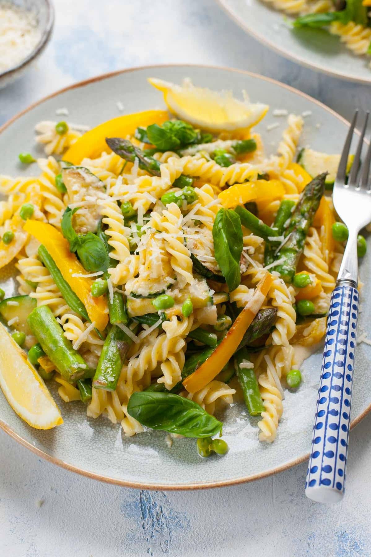 close up view on pasta primavera on a blue plate with a blue fork