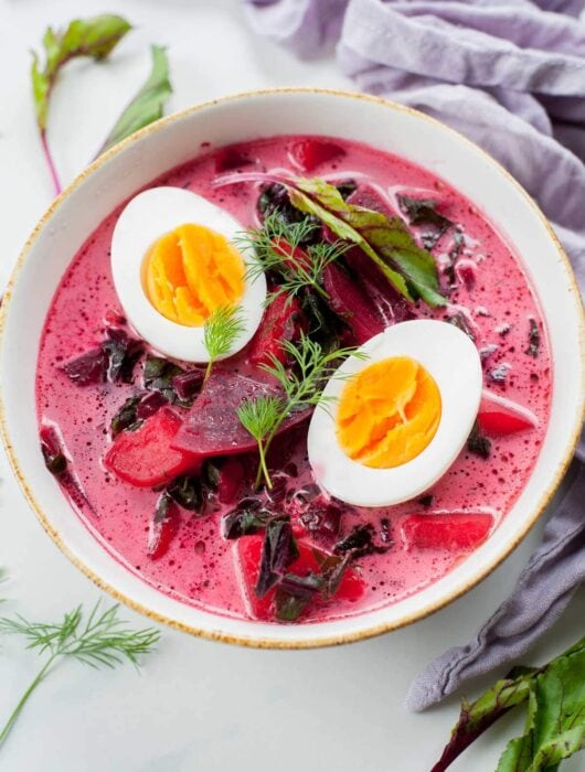 young beet soup in a white bowl, cooked eggs and dill in the soup