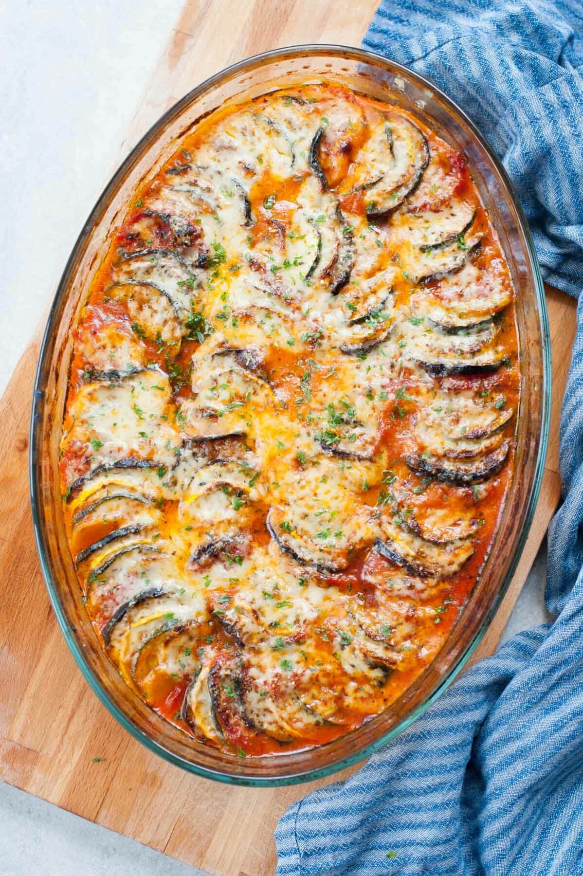 Baked ratatouille (confit byaldi) in a translucent baking dish, sprinkled with parsley.