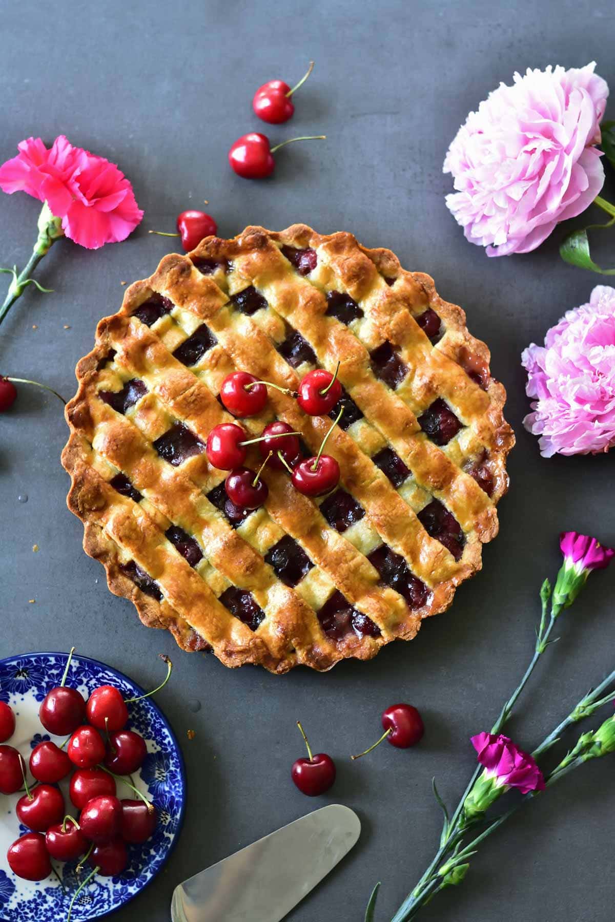 cherry tart with chocolate on a black background with cherries and flowers