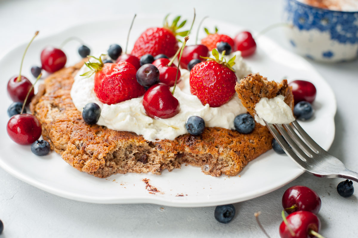 omlet czekoladowy z bitą śmietaną i owocami na białym talerzu