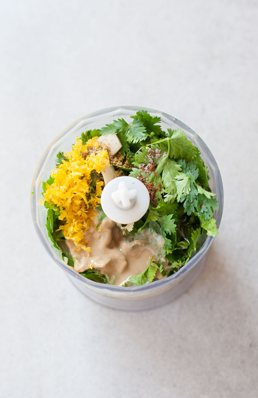 ingredients for green tahini sauce in a food processor container (not mixed yet)