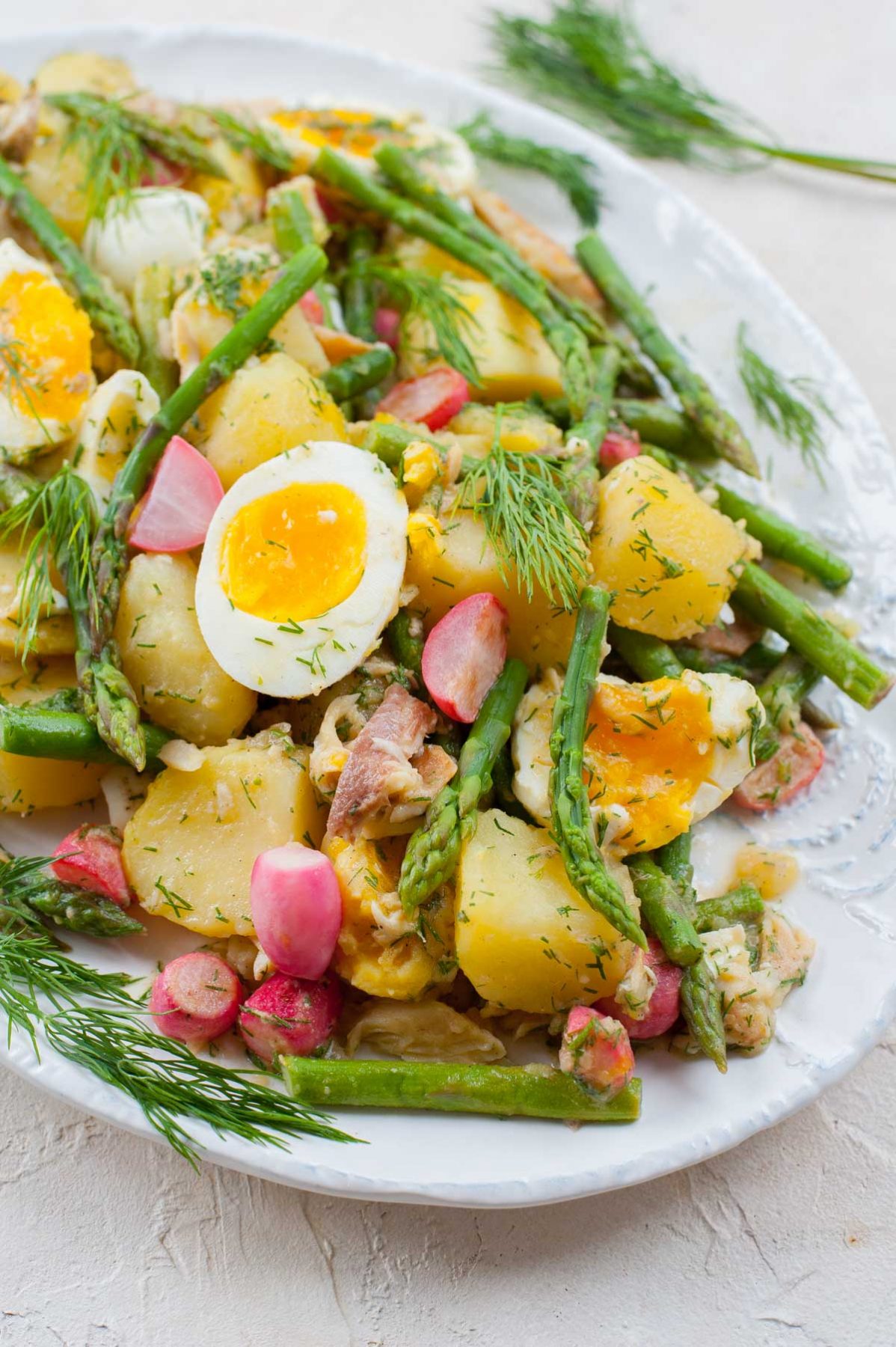 close up photo of potato and asparagus salad on a white plate