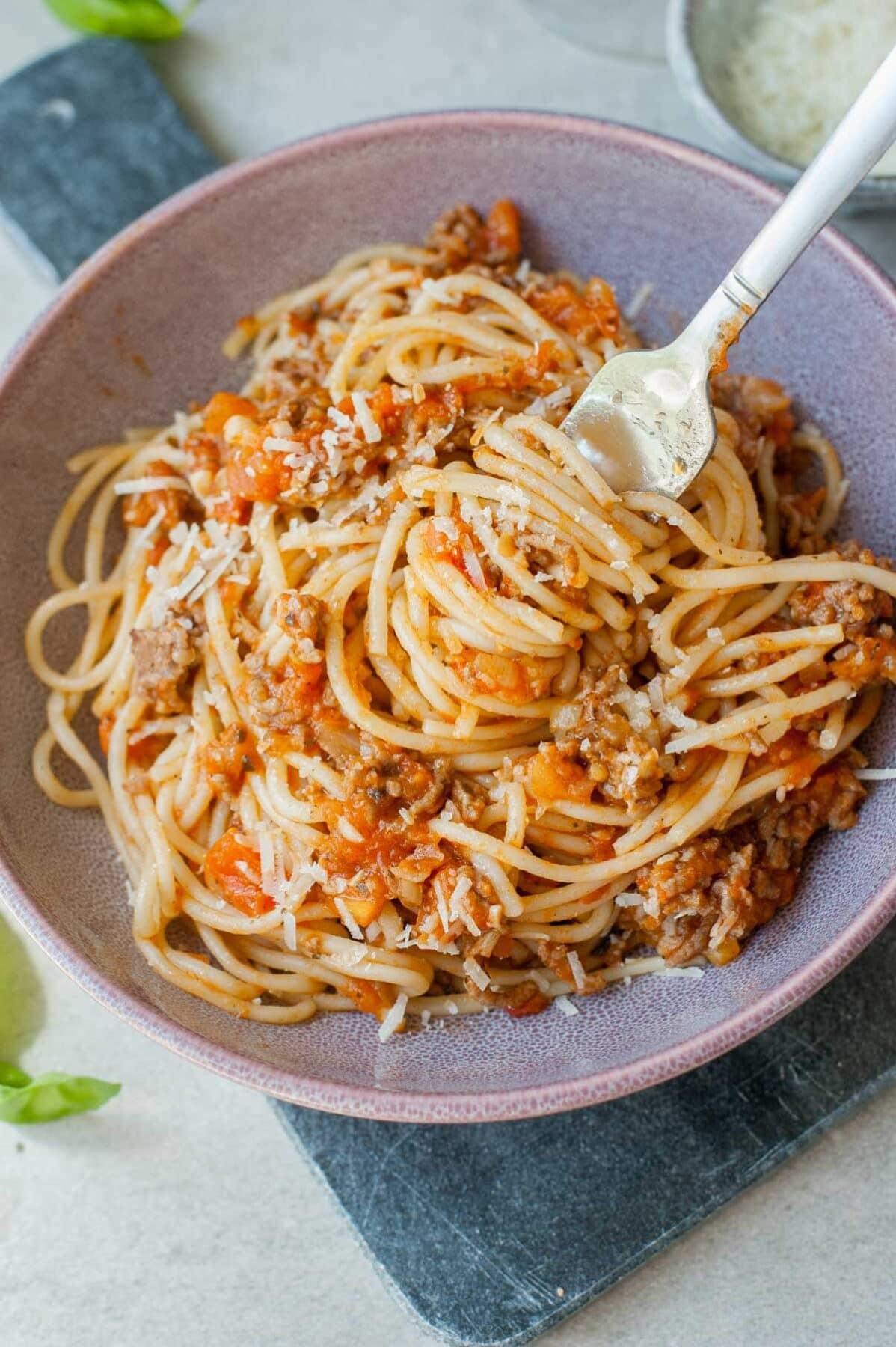 quick spaghetti with fresh tomato meat sauce on a fork in a violet bowl