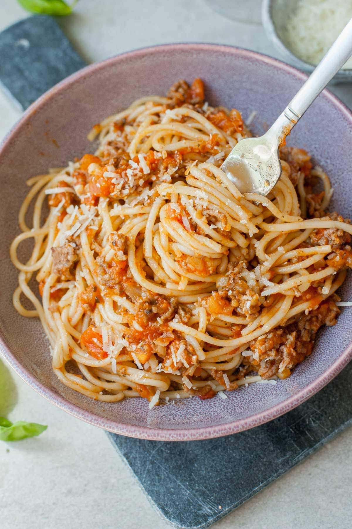 spaghetti with fresh tomato meat sauce on a fork in a violet bowl
