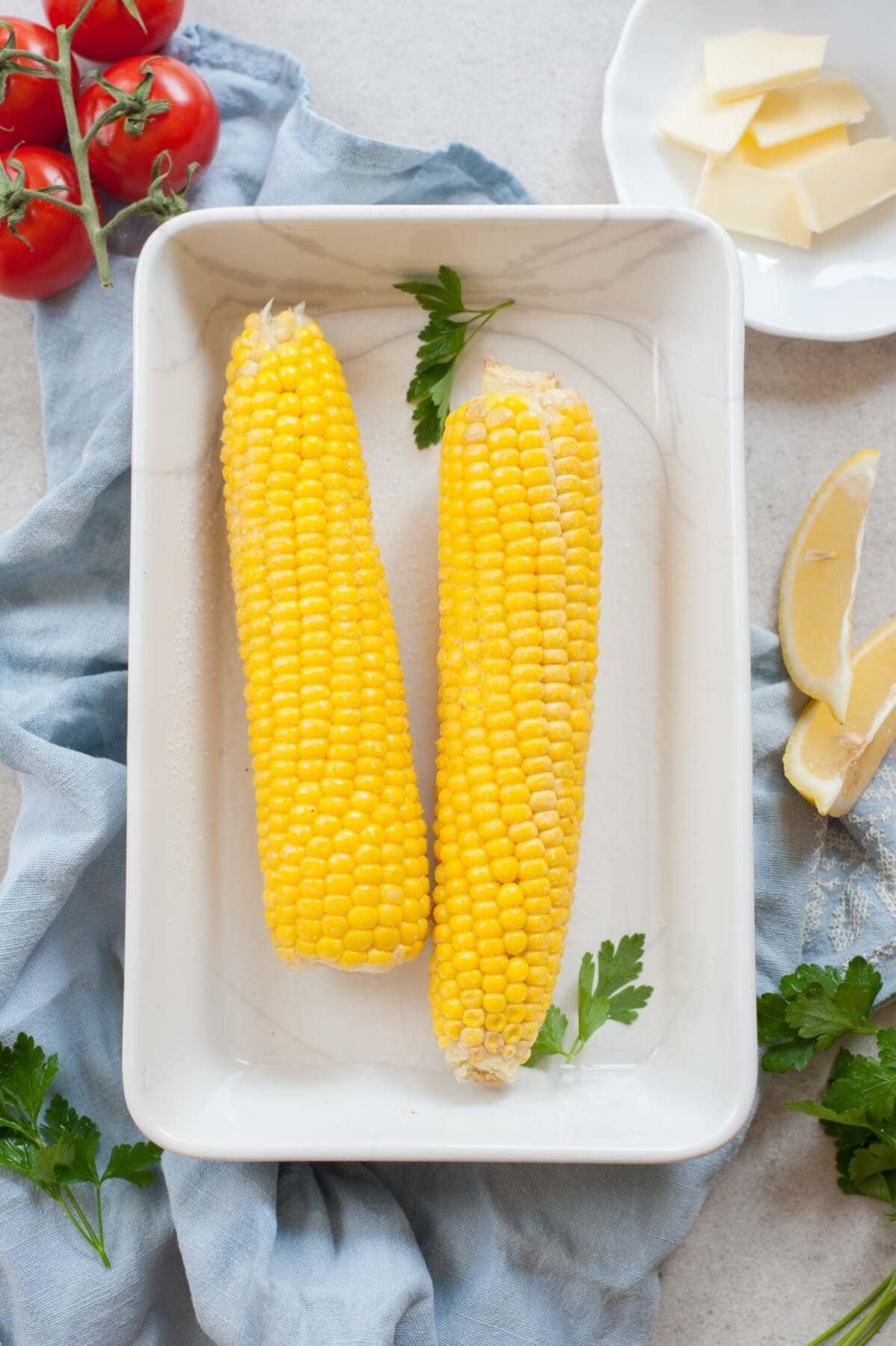 overhead picture of corn in a white baking dish on a blue kitchen towel