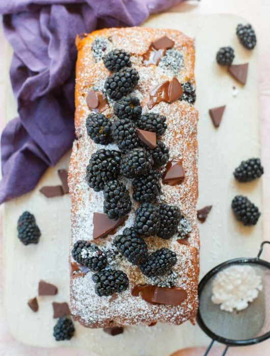 whole blackberry banana bread with chocolate on a wooden board