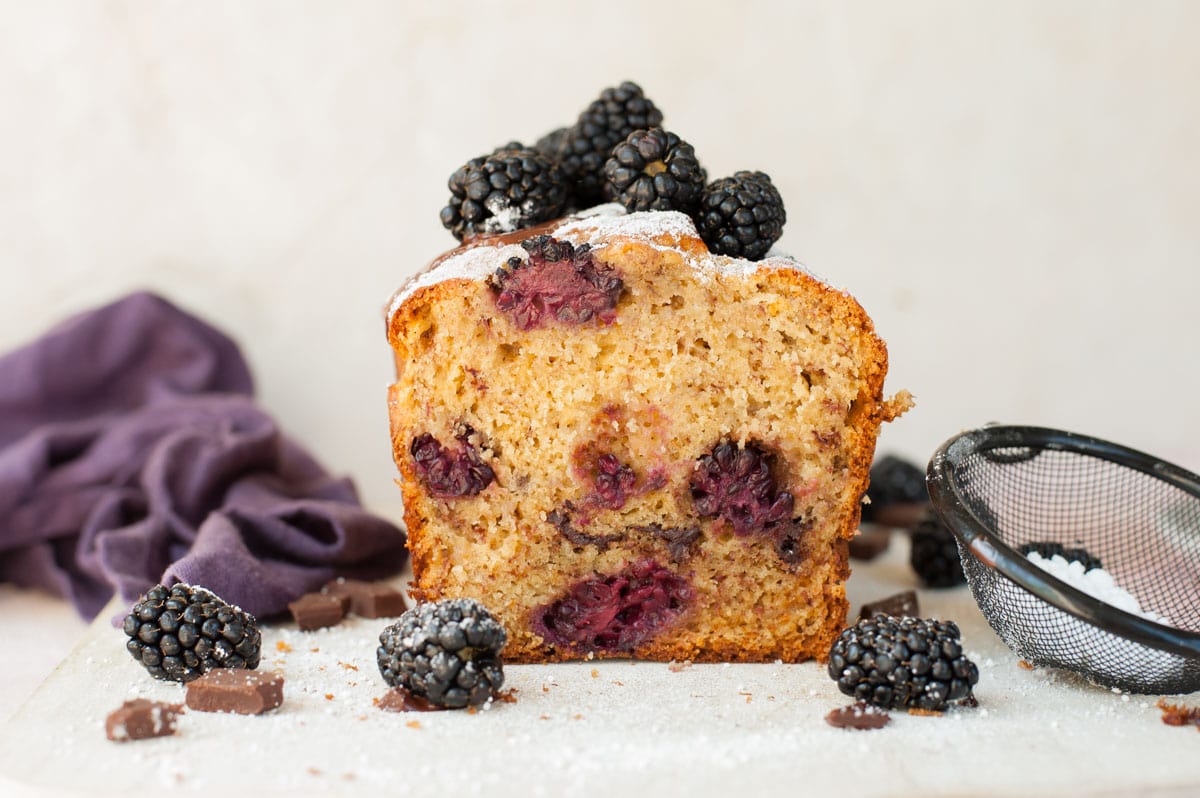 blackberry banana bread cut in half on a wooden board