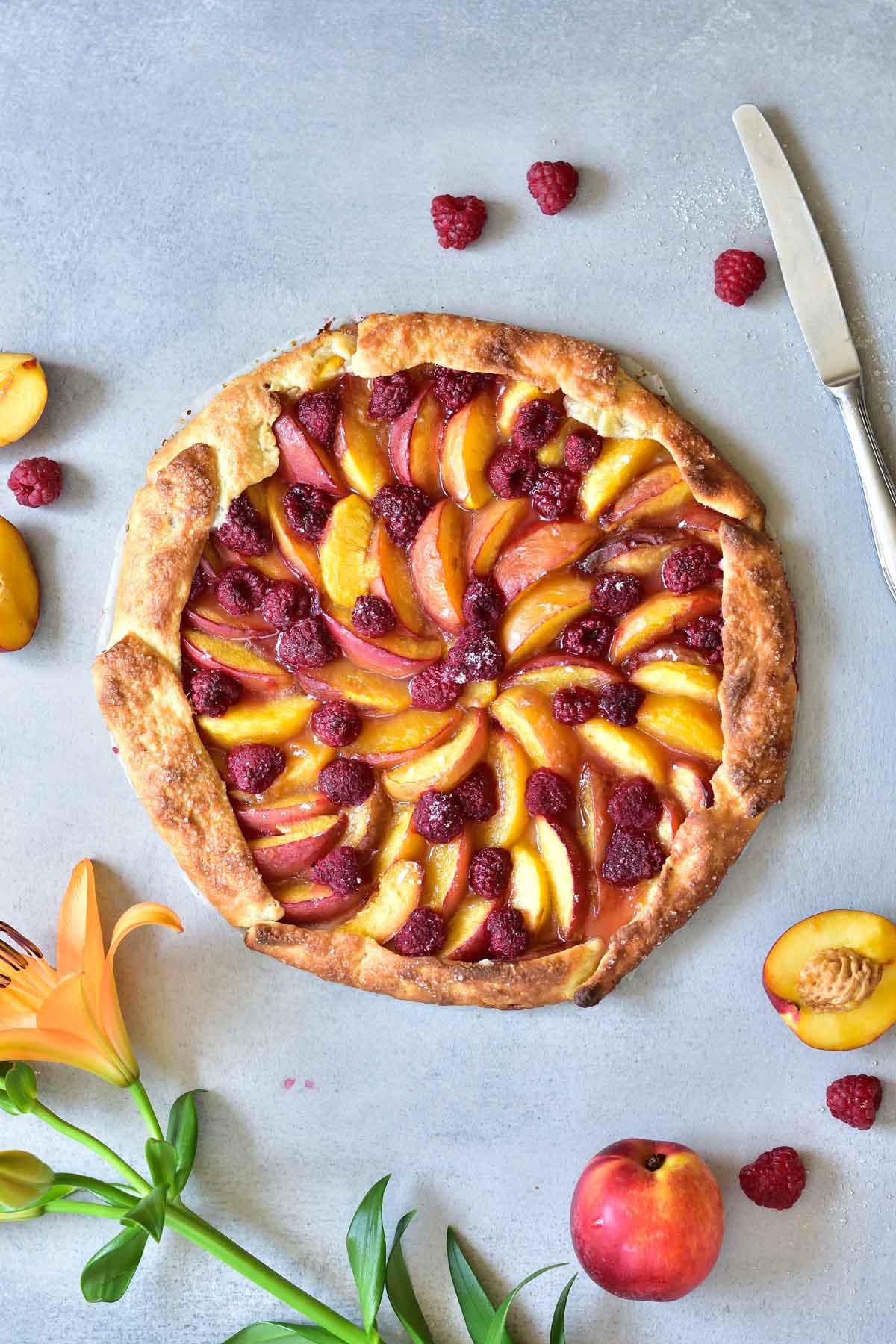 nectarine galette with raspberries on a blue background