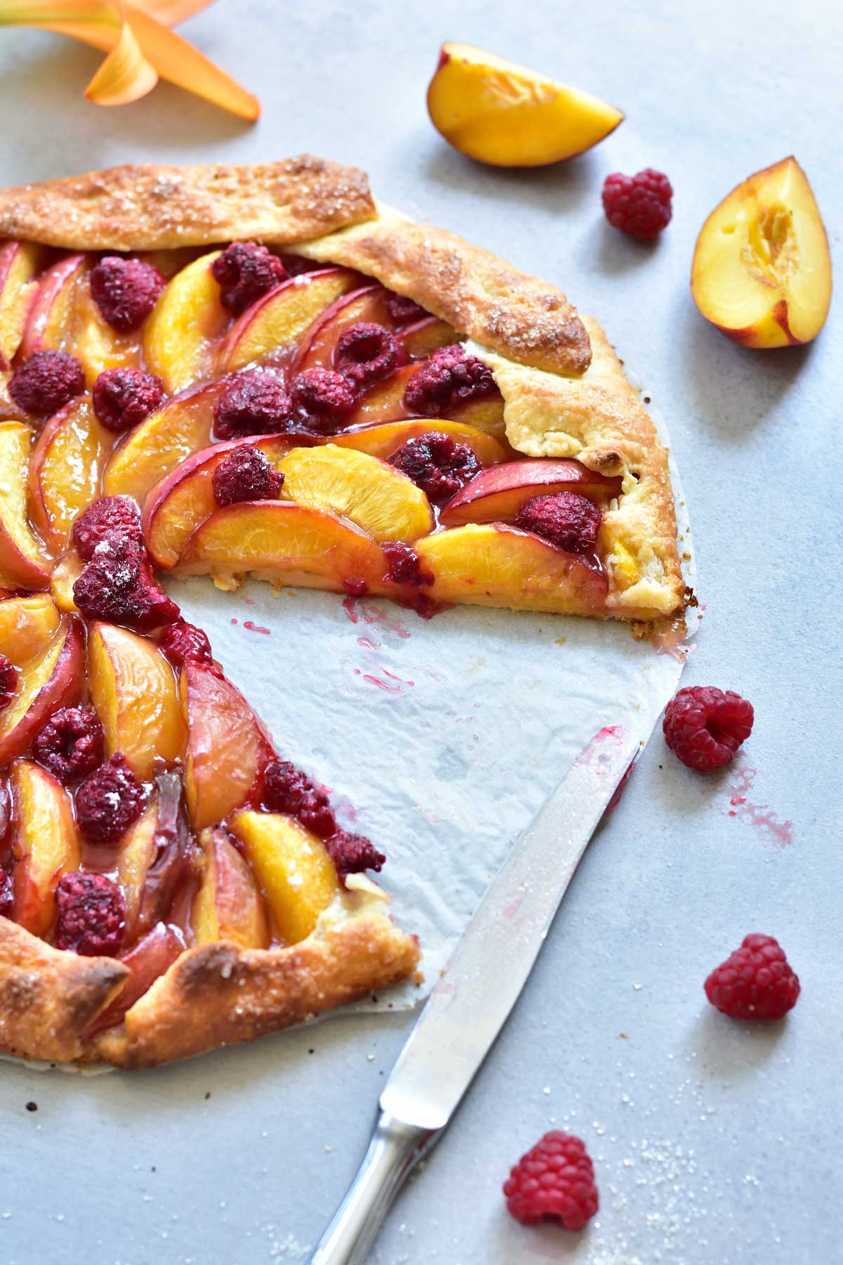 nectarine galette with a piece missing on a blue-grey background