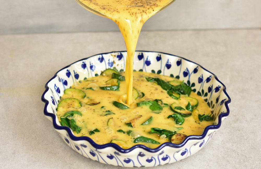 Whipped eggs are being poured into a baking dish.