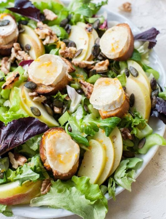 Apple celery salad with walnuts and goat cheese on a white plate.