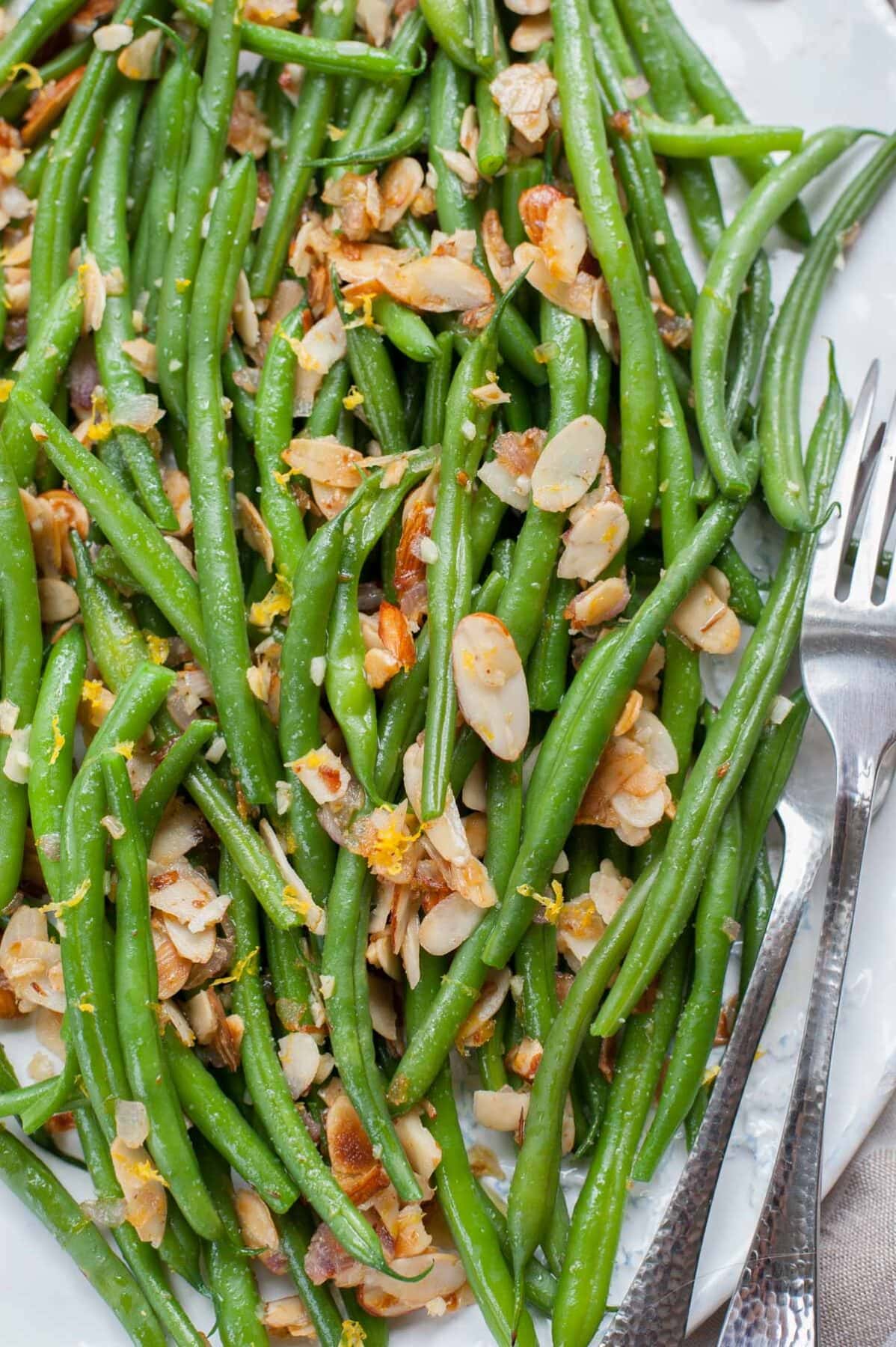 close up picture of Green beans almondine on a white plate