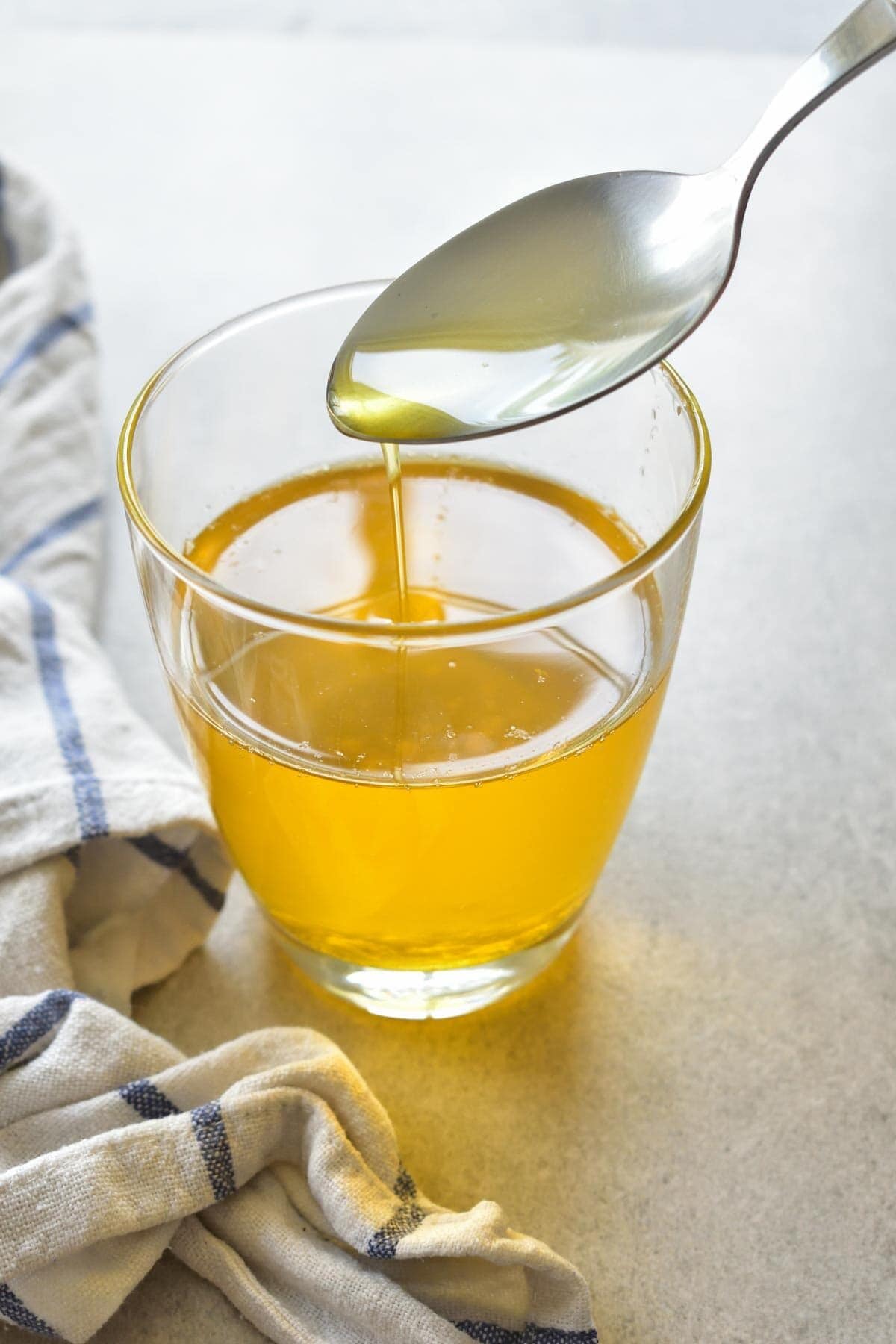 Clarified butter is being spooned into a glass.