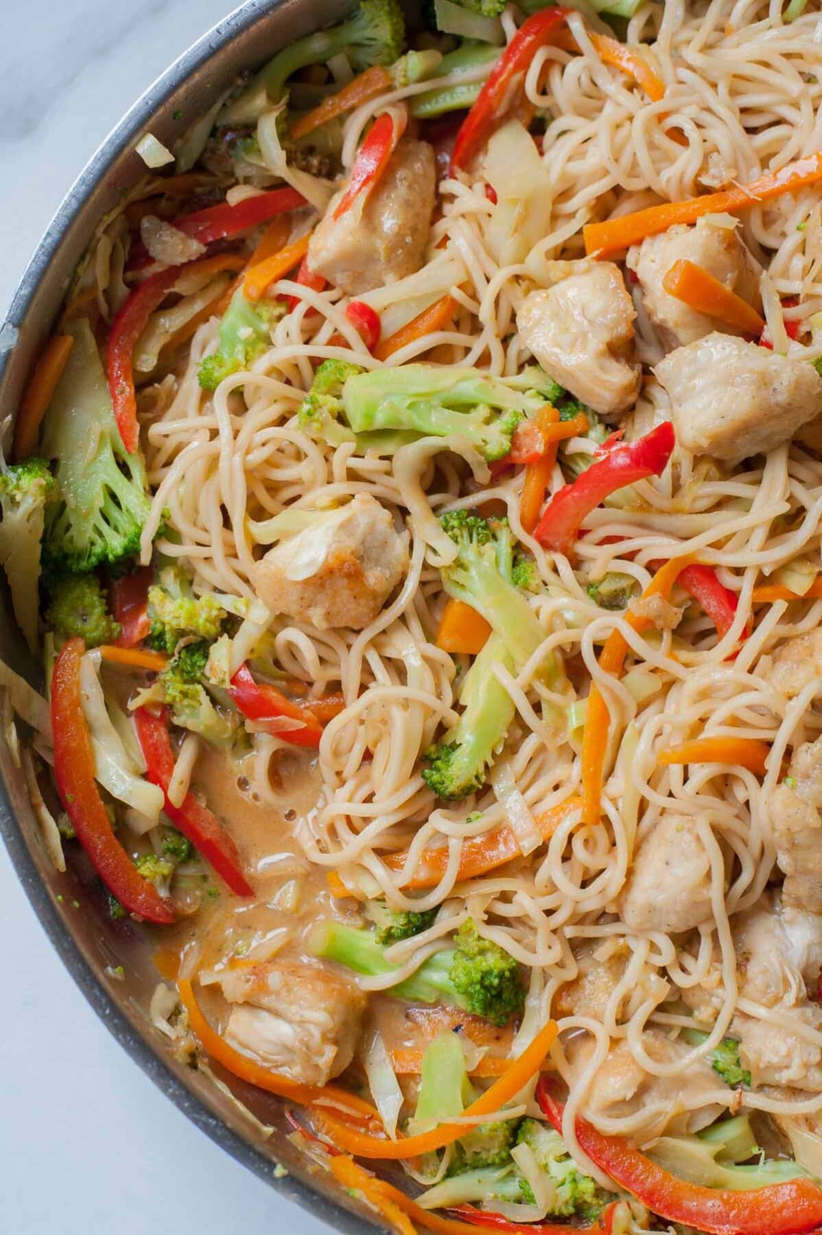 a closeup picture of peanut chicken noodles with vegetables in a frying pan